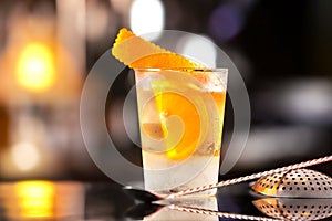 Closeup glass of old fashioned cocktail decorated with orange