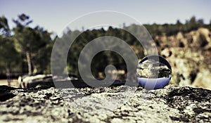 Closeup of a glass sphere on a rock with an upside down reflection of its surroundings