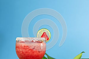 Closeup of a glass of strawberry daiquiri cocktail on a blue background