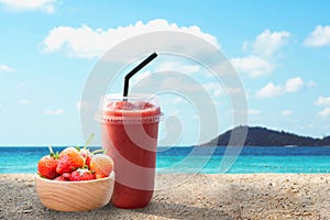 Closeup glass of strawberry smoothie with lignt in the morning and sea water background, Holiday and relax time