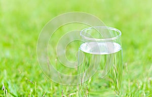 Closeup glass of water on green grass nature background, food healthy concept