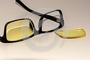 Closeup of glasses with a black broken rim on a white surface