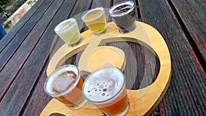 Closeup with glasses with different sorts of craft beer on wooden table.