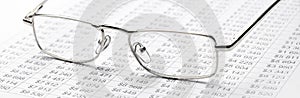 closeup glasses on financial newspaper under light tint blue