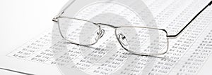 closeup glasses on financial newspaper under light tint blue