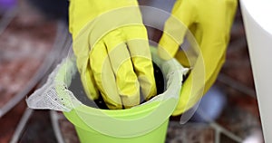 Closeup of gloved hands stirring soil in flowerpot
