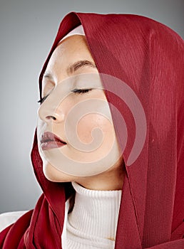 Closeup of a glowing beautiful muslim woman with eyelash extensions isolated against grey background in studio. Young