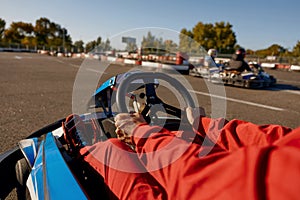 Closeup go-kart racer driving sportcar, focus on hands holding steering wheel