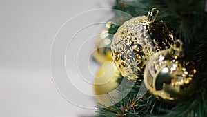 Closeup of gold bauble hanging from a decorated Christmas tree