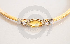 Closeup gold bracelet with yellow pebble on gray marble stone background