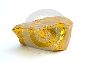 Closeup of gold nugget or gold ore on white background, precious stone or lump of golden stone, financial and business concept photo