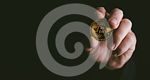 Closeup of golden bitcoin BTC cryptocurrency in hand over dark black background