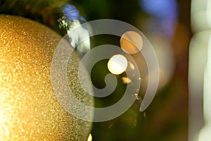 Closeup golden Christmas Balls Decorated on Pine Tree on Christmas day with bokeh of led lighting and blurry background