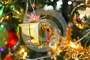 Closeup Golden Gift Box on Christmas Tree Background. Merry christmas and Happy New Year concept