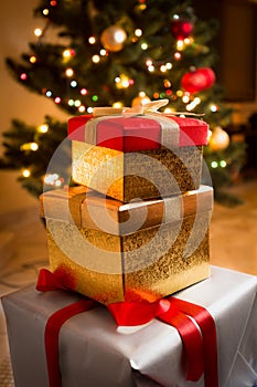 Closeup of golden and red gift boxes under Christmas tree