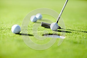 Closeup, golf and ball with club for shot in hole for practice, exercise or wellness to relax on grass. Sports, course