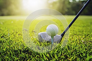 closeup golf club and golf ball on green grass wiht sunset