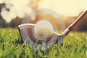 closeup golf club and golf ball on green grass wiht sunset