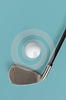 Closeup of golf club and golf ball isolated on light turquoise blue background