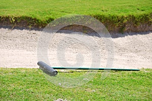 Closeup of a golf course sand trap and rake