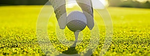 Closeup of golfer wearing glove placing golf ball on a tee at golf course