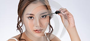 Closeup gorgeous woman putting black mascara on her long eyelashes with brush.