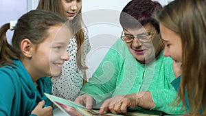 Closeup of grandmother showing old photo album to her granddaughters