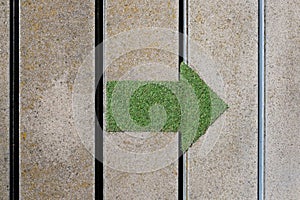 Closeup of a green arch on a sunlit wall marking the direction