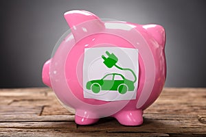 Closeup Of Green Electric Car On Pink Piggybank