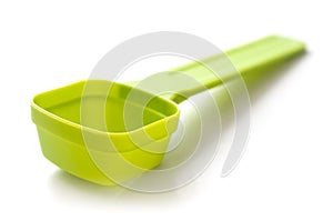 Green plastic dose spoon on white background