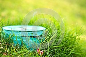 Closeup of green plastic pipe with cover on green grass lawn