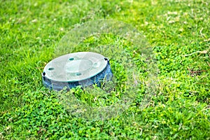 Closeup of green plastic pipe with cover on green grass lawn