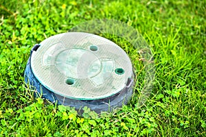 Closeup of green plastic pipe with cover on green grass lawn
