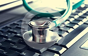 Green stethoscope lying on a blue notebook keyboard (selective focus) photo