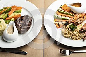 Closeup of grilled beef steaks and Grilled King prawns or shrimps with noodles