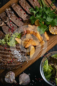 Closeup of grilled meat set with potatoes on wooden board