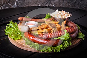 Closeup of grilled sausages with french fries, ketchup and side salad decorated with lettuce