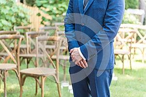 Closeup of a groom in a blue suit waiting for a bride in a garden
