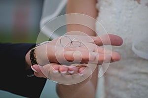 Closeup of the groom holding the wedding rings on the palm of his hand above the bride's hand
