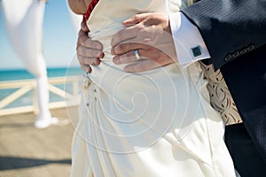 A closeup of the grooms hand with a wedding ring as he holds his