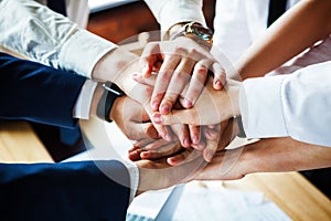 Closeup of a group of businesspeople joining their hands together.