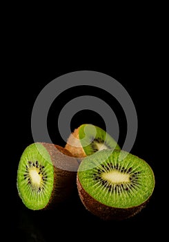 Closeup of a group of open green kiwis on black background,