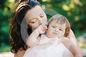 Closeup group portrait of beautiful white Caucasian brunette mother holding hugging daughter kissing her in cheek