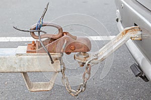 Closeup grungy tow car with connected hook and chain.