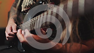 Closeup of guitar strings and neck. Guitarist playing rock, metal by beautiful eight string guitar in the room with neon