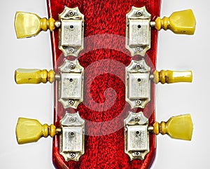 Closeup of guitar tuner or tuning pegs on red headstock.  Classic old school vintage kluson deluxe double ring circa 1966 on