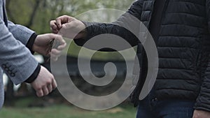 Closeup guy gives car keys to customer and shake hands. Auto business, car sale, deal, gesture and people concept.