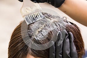 Closeup of hair dresser applying chemical color dye onto hair