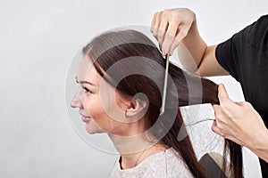 Closeup of hair stylist combing client`s hair in salon