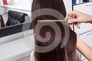 Closeup of hair stylist combing client`s hair in salon